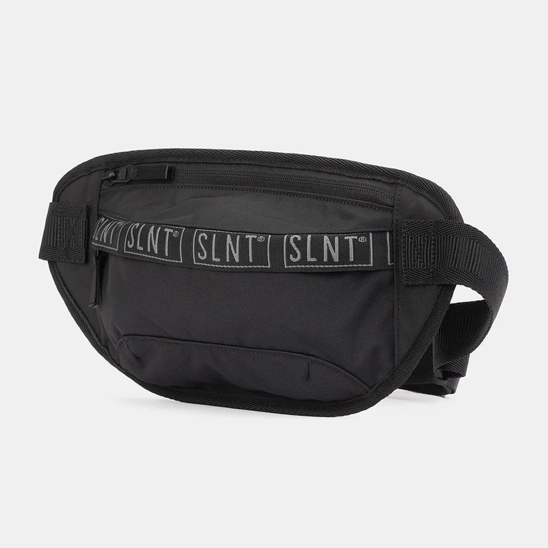 The SLNT Faraday Essential Sling Bag by SLNT is a black waist bag with a front zipper pocket, black strap, and a strip featuring repeated white SLNT text. Product shown on a plain white background.