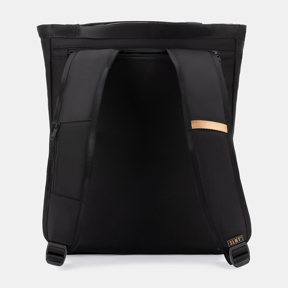 The SLNT E3 Faraday Tote Bag (17L) by SLNT is shown from the back, featuring padded shoulder straps, a top zipper, a small tan accent on one strap, and a SLNT logo label on the lower right strap.