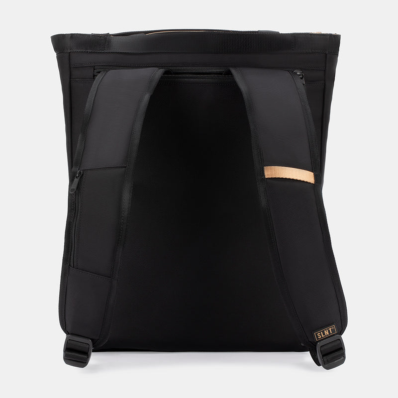 The SLNT E3 Faraday Tote Bag (17L) by SLNT is shown from the back, featuring padded shoulder straps, a top zipper, a small tan accent on one strap, and a SLNT logo label on the lower right strap.
