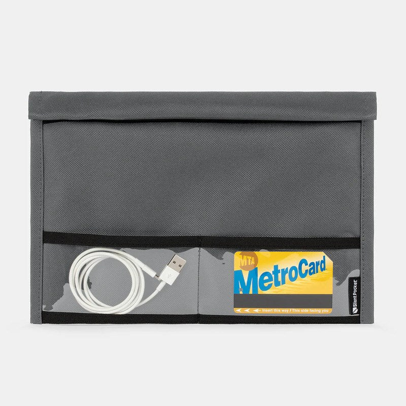 The SLNT Utility Faraday Bag XL by SLNT is a gray fabric bag with two clear front pockets—one contains a white USB cable, the other displays a yellow and blue MTA MetroCard—and provides signal blocking for enhanced data security.
